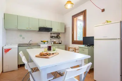 a kitchen with a white table and a white refrigerator at Pittalumari Makari in Macari