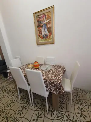 a dining room table with white chairs and a painting at SPYDA in Palermo