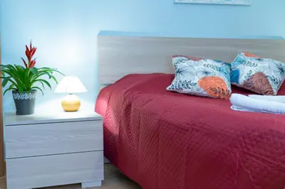 a bedroom with a bed with a red comforter and a plant at Happie Casa Il Capo & La Cattedrale in Palermo