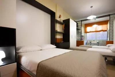 a bedroom with two beds and a living room at M'Place - Mondello Residence in Palermo