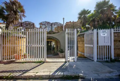 a white gate in front of a building with palm trees at M'Place - Mondello Residence in Palermo