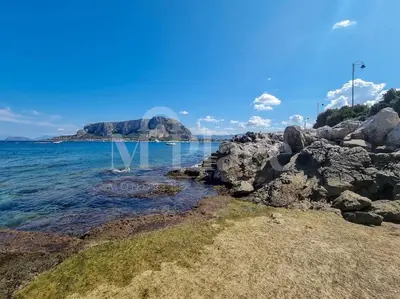 a rocky shore with an island in the water at M'Place - Mondello Residence in Palermo
