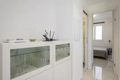 a white kitchen with a counter with glasses on it at Federica's House - Sporting Village in Scopello