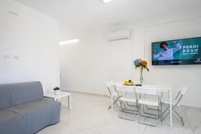 a living room with a table and a tv on the wall at Federica's House - Sporting Village in Scopello