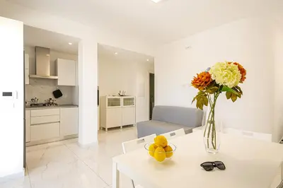 a white living room with a vase of flowers on a table at Federica's House - Sporting Village in Scopello