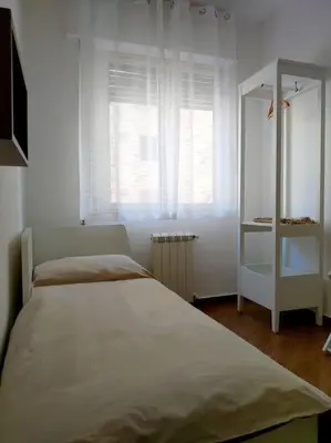 a white bedroom with a bed and a window at Appartamento Ai Murales in Palermo