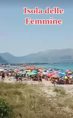 a group of people standing on a beach with umbrellas at Casa Alice in Isola delle Femmine
