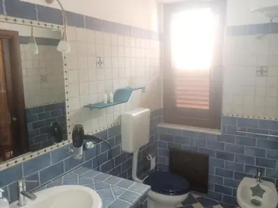 a blue tiled bathroom with a toilet and a sink at Casa Alice in Isola delle Femmine