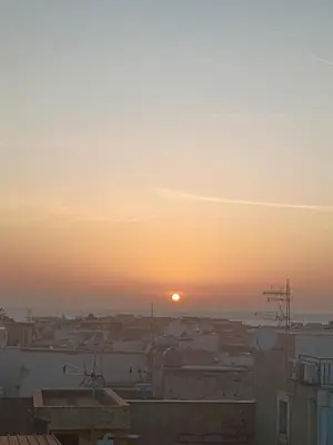 a sunset over a city with the sun setting at Casa Alice in Isola delle Femmine