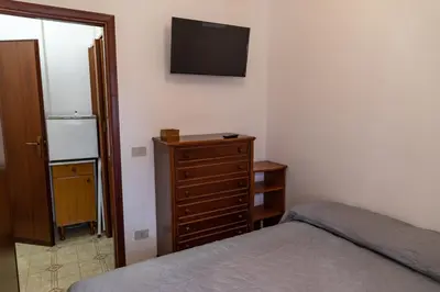 a bedroom with a bed and a dresser with a television on the wall at L'isola Che Non C'è in Isola delle Femmine