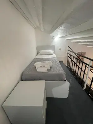 a small white room with a bed and a bench at RC SUITE TERMINI IMERESE in Termini Imerese