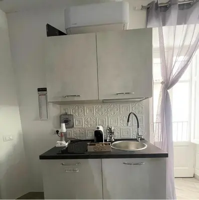 a kitchen with white cabinets and a sink and a window at RC SUITE TERMINI IMERESE in Termini Imerese
