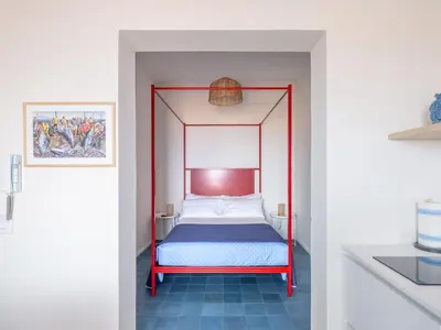 a bed with a red frame in a room at Piricù Apartments in Castellammare del Golfo