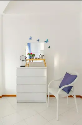 a white dresser with a chair and a mirror at Riva Home Il tuo angolo di paradiso in Sicilia ti aspetta! Prenota ora e vivi la magia del Mediterraneo!