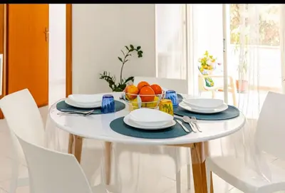 a white table with a bowl of oranges on it at Riva Home Il tuo angolo di paradiso in Sicilia ti aspetta! Prenota ora e vivi la magia del Mediterraneo!