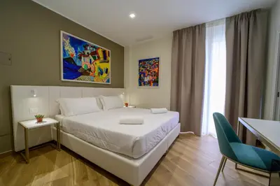 a bedroom with a white bed and a blue chair at B&B Maqueda - Room & Suite in Palermo