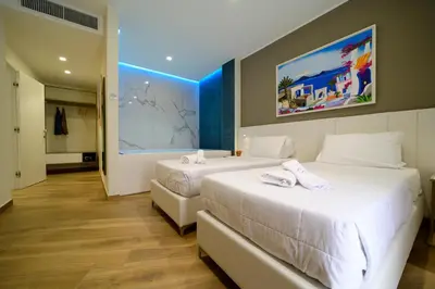 two beds in a hotel room with white sheets at B&B Maqueda - Room & Suite in Palermo