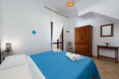 a bedroom with a blue bed with towels on it at Villa levante Macari in Macari