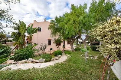 a garden in front of a pink house with trees at Villa levante Macari in Macari