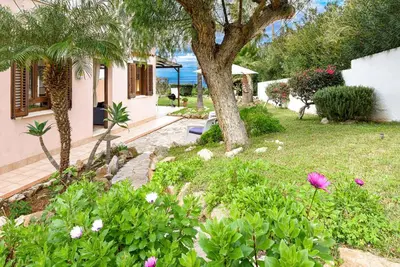 a garden with flowers and a tree and a house at Villa levante Macari in Macari