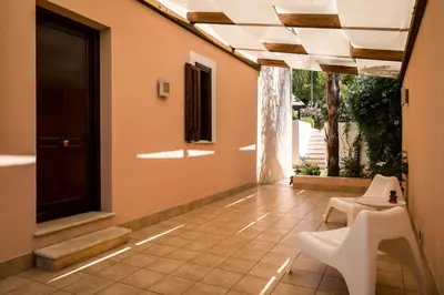 a patio with two white chairs and a window at Villa Grecale Macari in Macari