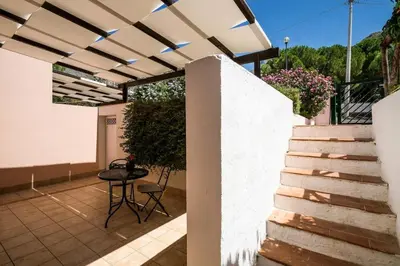 a patio with a white wall and stairs and a table at Villa Grecale Macari in Macari