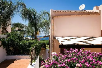 a patio with pink flowers in front of a building at Villa Grecale Macari in Macari