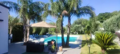 a person sitting in a chair next to a swimming pool at Appartamento uso turistico Villa Barbara in Carini