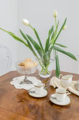 a wooden table with cups and a vase with flowers at Palazzo Ventimiglia Lodge & Suites in Palermo