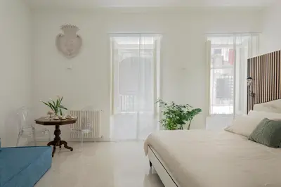 a white bedroom with a bed and a table at Palazzo Ventimiglia Lodge & Suites in Palermo