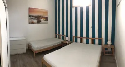 a small room with two beds and a striped wall at Appartamento Trilocale Mondello in Mondello