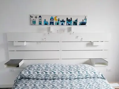 a bedroom with a bed and a white wall at Casina Blu in Palermo