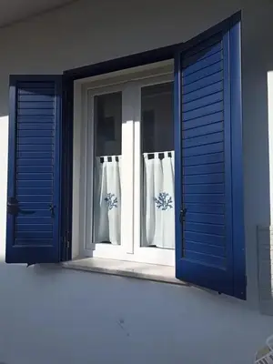 an open window with blue shutters on a house at Casa delle Sirene in Isola delle Femmine