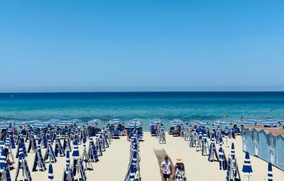 a beach with chairs and umbrellas and the ocean at Casa delle Sirene in Isola delle Femmine