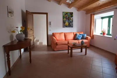 a living room with an orange couch and a table at Vito nel Baglio in Scopello