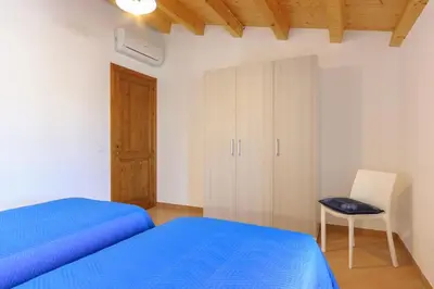 a bedroom with a blue bed and a chair at Vito nel Baglio in Scopello