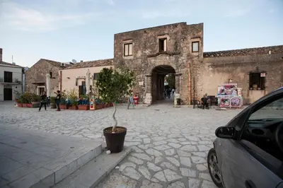 a car parked in front of a building with a tree in a pot at Vito nel Baglio in Scopello