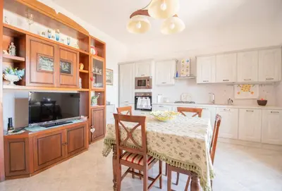 a kitchen with a table and chairs and a television at A pochi passi dal mare in San Vito lo Capo