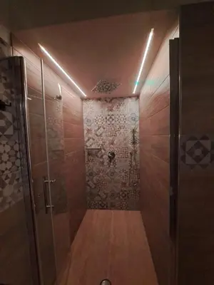 a bathroom with a walk in shower with a wooden floor at Colle del Re Sicily in Partinico