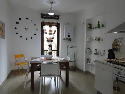 a kitchen with a table and chairs and a clock on the wall at A Casa di Eli Apartment in Palermo