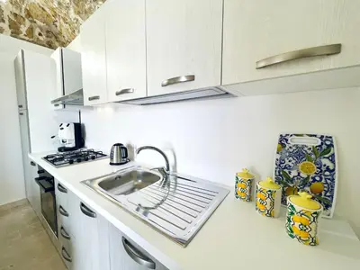 a white kitchen with a sink and a stove at Magaggiari Reef in Cinisi