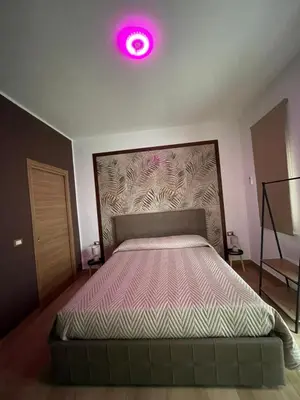 a bedroom with a bed with a pink light above it at RESIDENCE GORDON in Carini