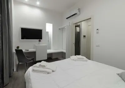 a white bedroom with a large bed and a desk at Blanc Rooms in Palermo