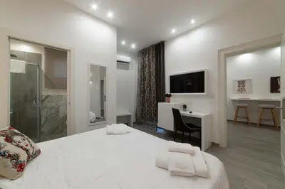 a white bedroom with a large bed and a desk at Blanc Rooms in Palermo