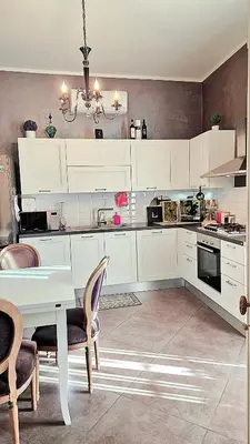 a kitchen with white cabinets and a table and chairs at La Baronessa in Palermo