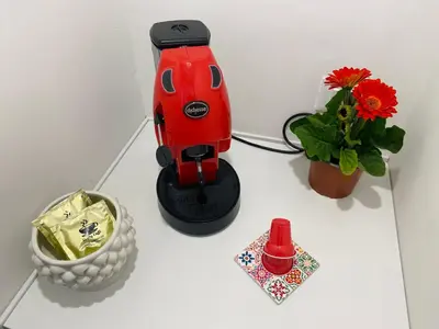 a red blender sitting on a white table with flowers at Attico Belvedere in Palermo