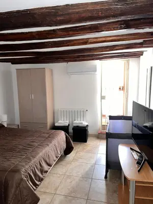 a bedroom with a bed and a desk and a tv at House del Corso in Palermo