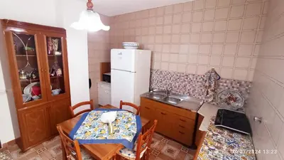 a kitchen with a table and a white refrigerator at AFFITTACAMERE LE SIGNORINE in Castellammare del Golfo