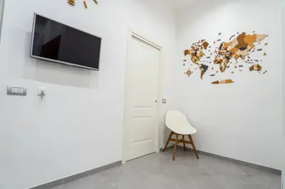 a white room with a chair and a tv on a wall at Nena Sweet Home in Palermo
