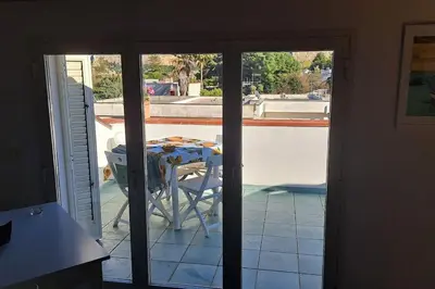a table and chair on a patio with a view of a pool at mansarda beach Mondello in Palermo